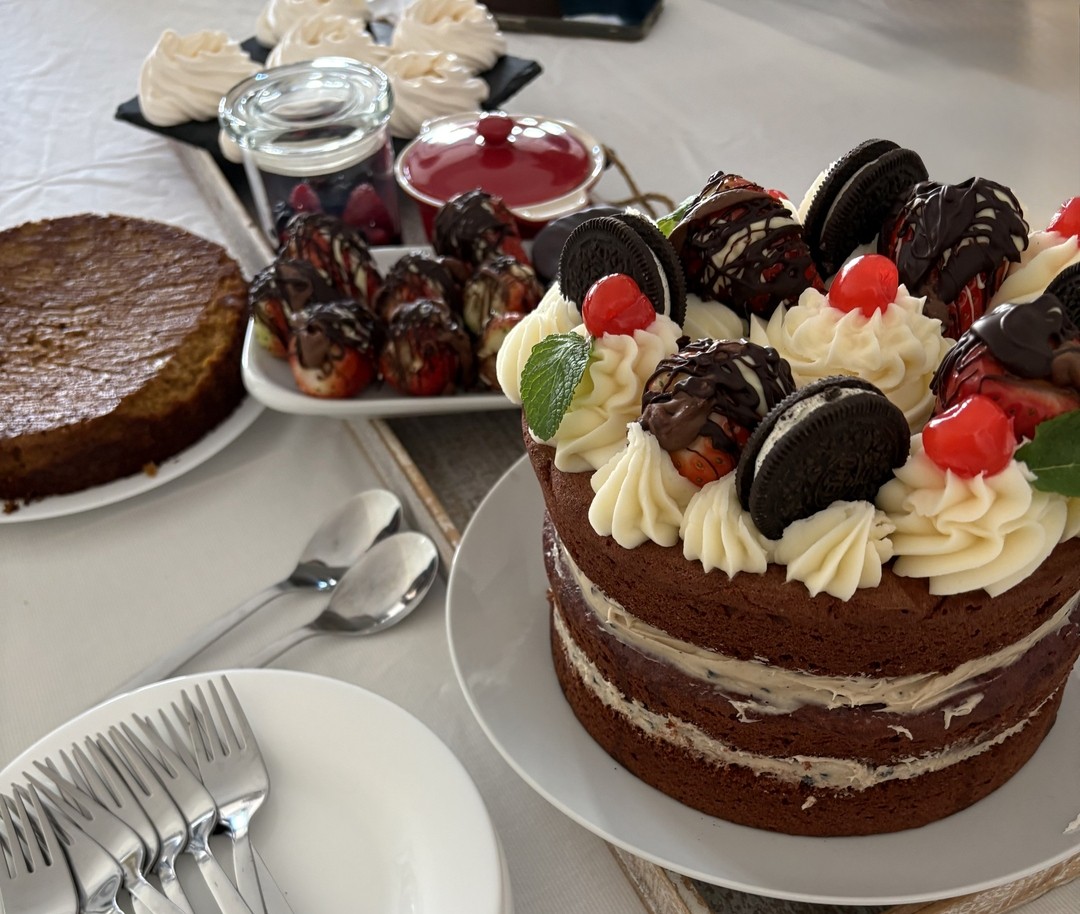 A dessert table with a decorated layered cake and chocolate-covered strawberries