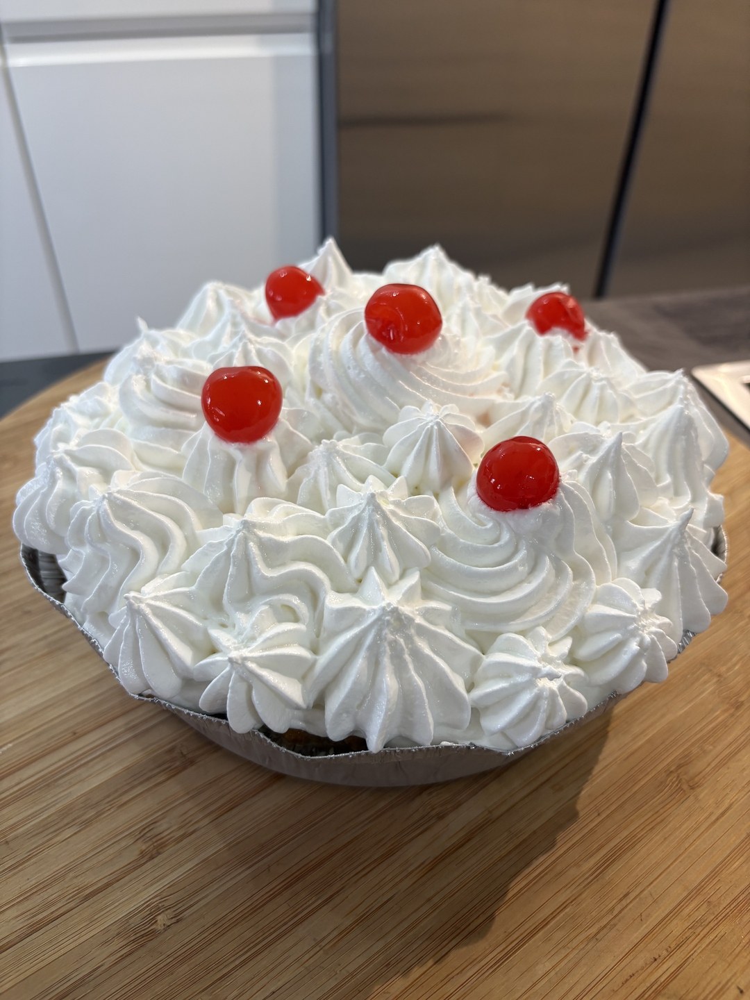 Spoonger tres leches cake topped with piped cream and red cherries